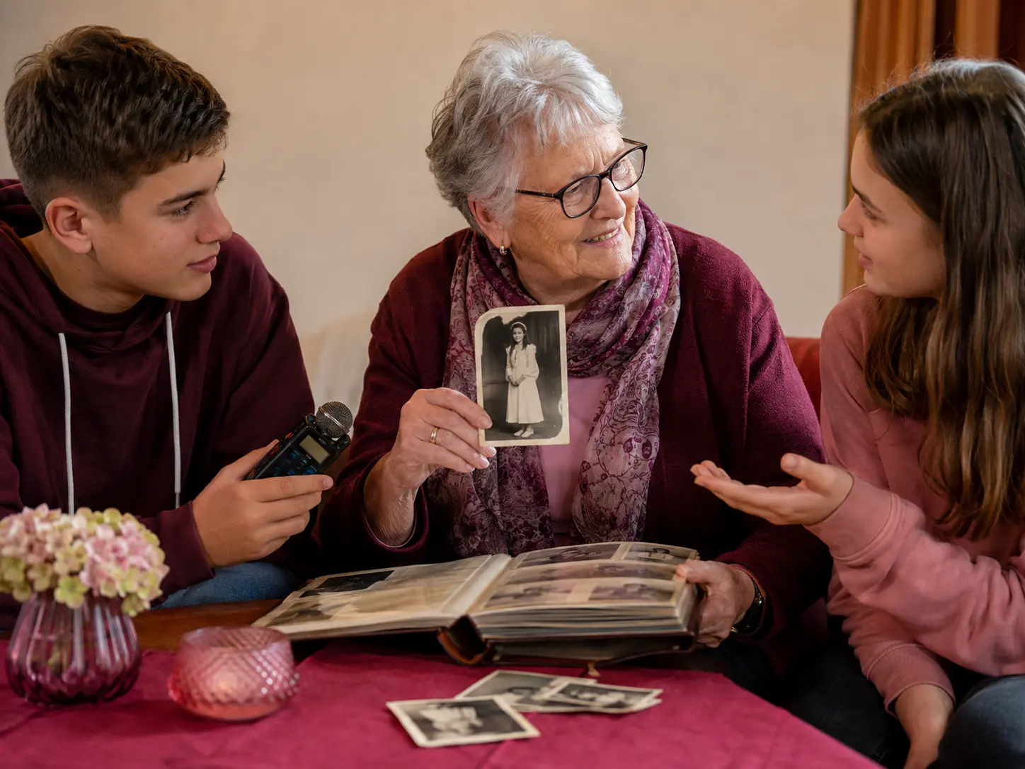 Eine ältere Frau zeigt Jugendlichen historische Konfirmationsfotos